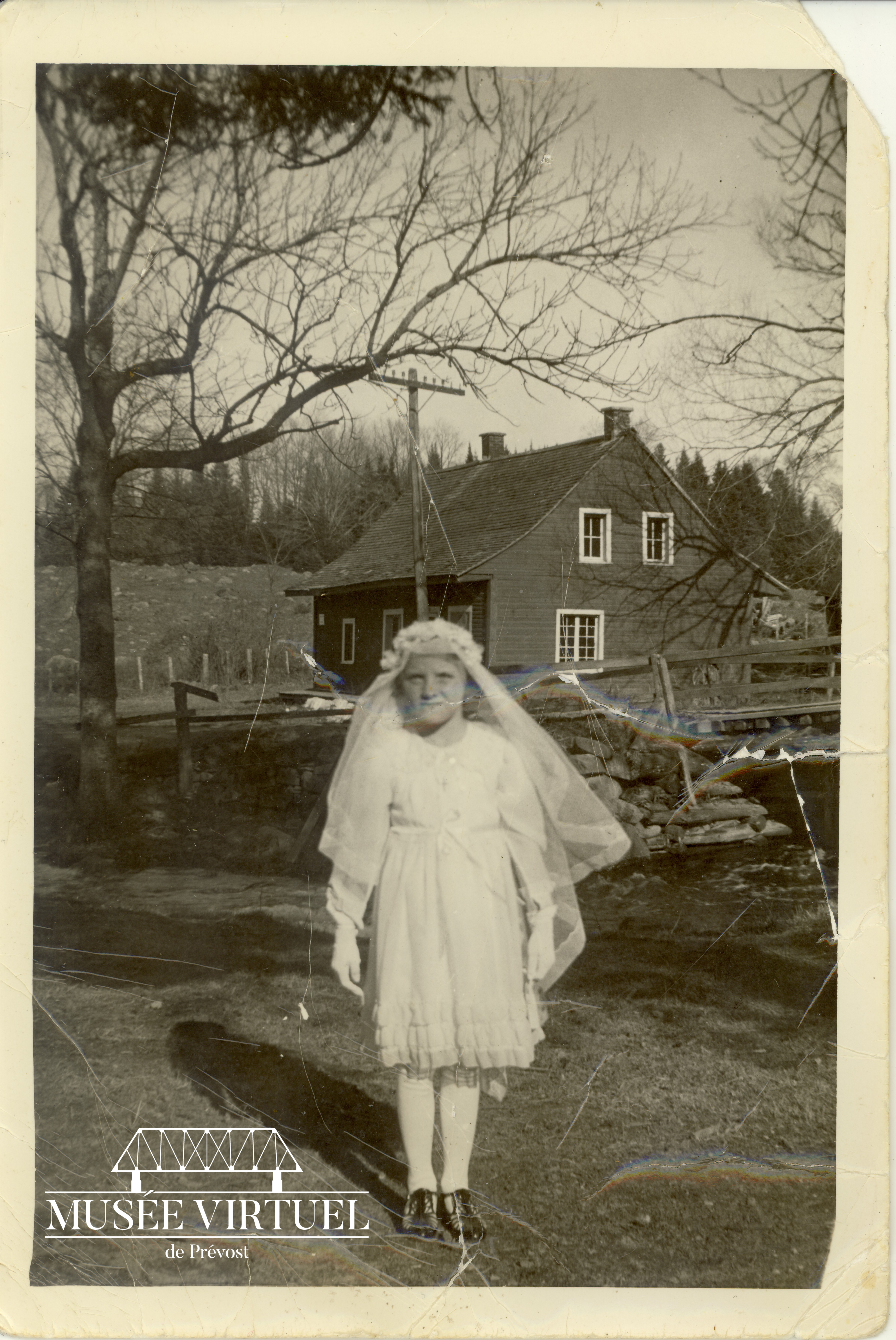 8. Première communion d'Annette Dagenais, fille d'Arthur Dagenais et Rose Lacasse, en 1939, alors qu'elle a 7 ans. La maison qu'on voit en arrière-plan est celle de son grand-père, Jean-Baptiste Dagenais - Collection de la famille Dagenais