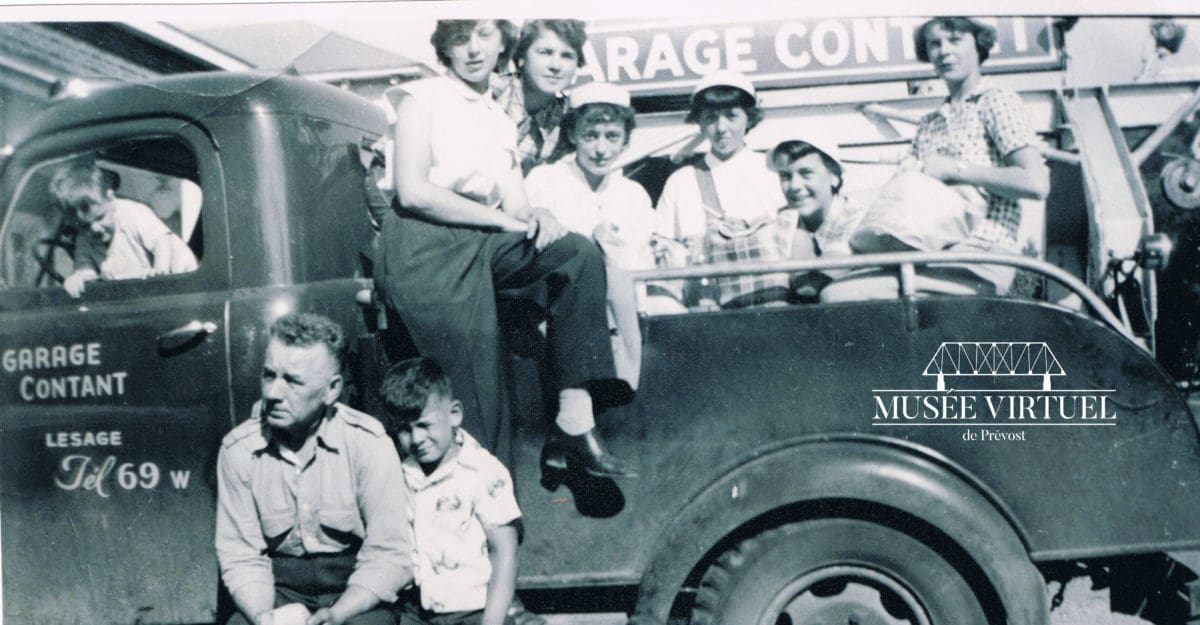 M. Émile Contant, entouré de Gaetan Contant à sa gauche, Jean-Pierre Contant, Isabelle Brosseau, Noella Rocheleau, Réjeanne Brosseau, Nicole Marchand, Lorraine Contant et Lorette Labelle à sa droite, devant le Garage Contant, près de la maison Lesage vers 1940 - Collection de Guy Thibault