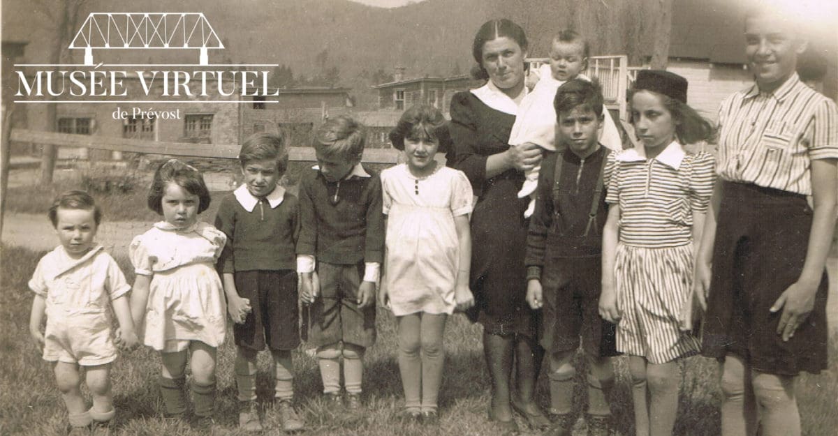 Famille de Marguerite Morin devant le Garage Morin vers 1940. On y voit Denis, Estelle, Claude, Gilberte, Cécile, Jean-Marie, Marie-Chantal, Bernadette, bébé Marie Rose dans les bras de maman Marguerite - Collection de Marie Morin