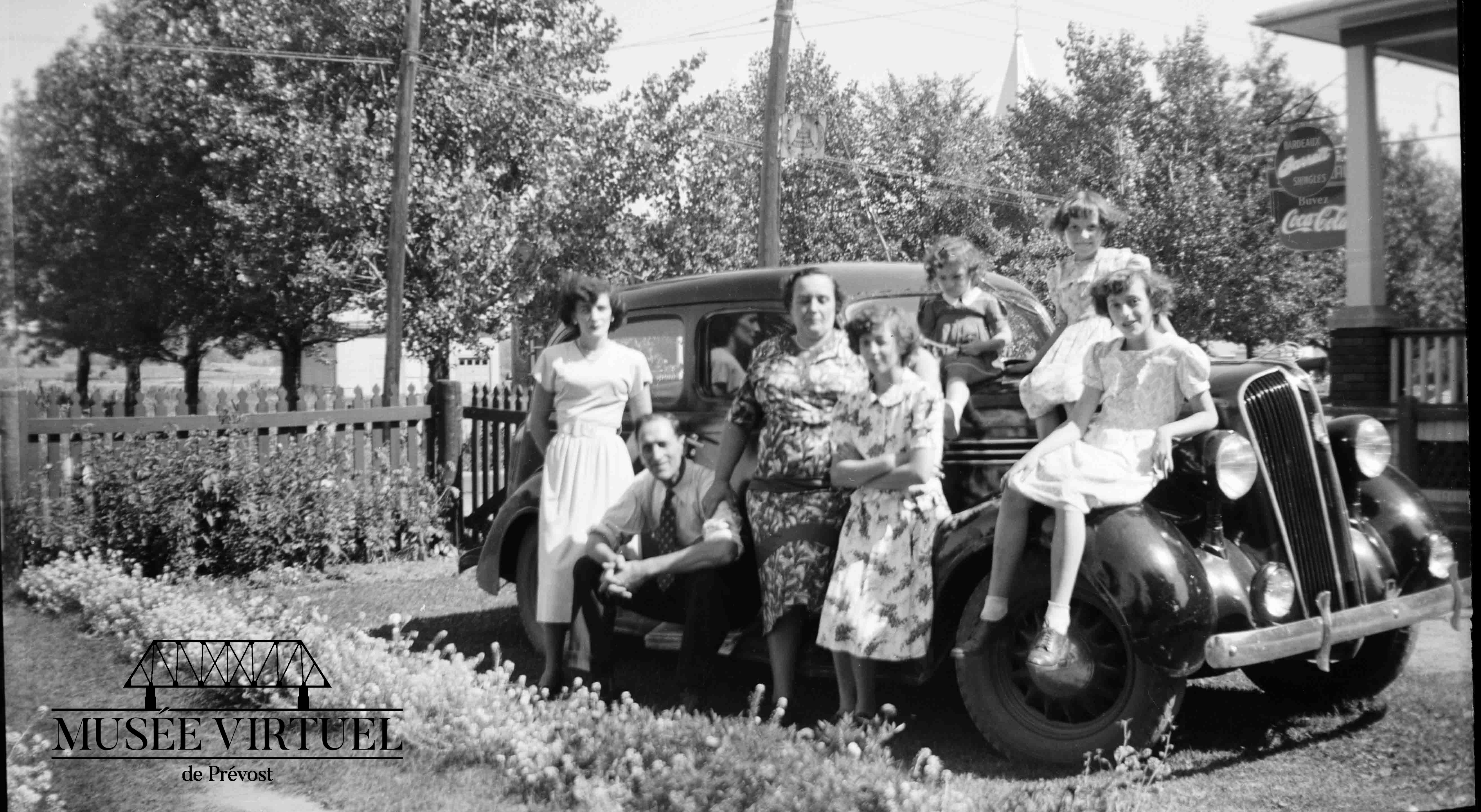7. Famille Brosseau : Aline, Isaë (assis), Délicia (sa femme), Isabelle, Béatrice, Gisèle et Réjeanne (assise sur l'aile) vers 1948-49 - Collection de la famille Brosseau