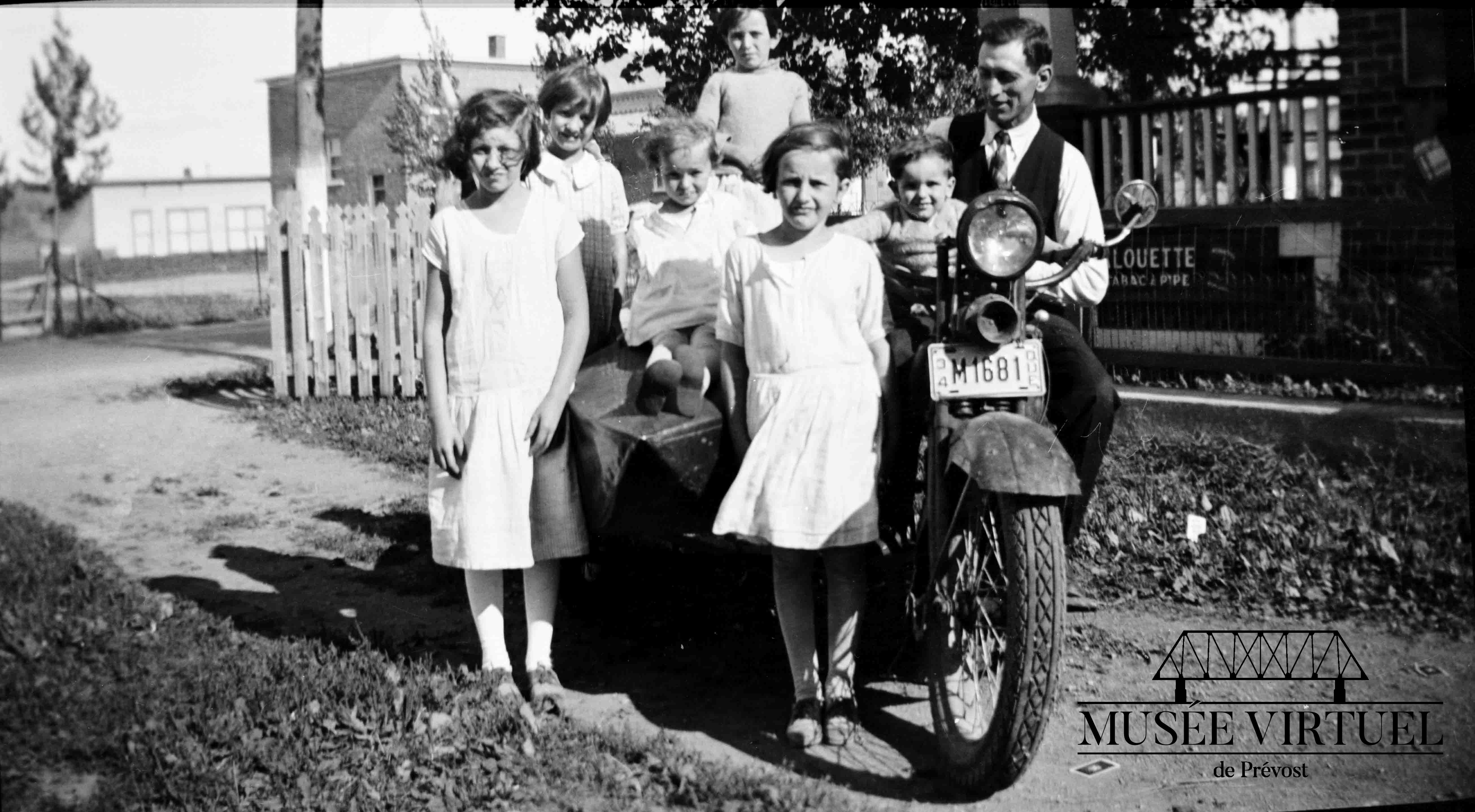 4. Sur la moto de papa en 1934. On y voit Aline, Marie, Lucille, Annette, Hélène, Eugène et Isaïe. Remarquez Isaïe qui regarde son fils unique avec un sourire fier - Collection de la famille Brosseau